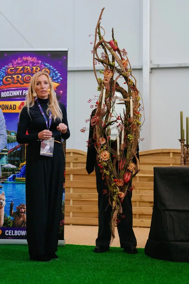 Florystka na scenie przy wysokiej instalacji z gałęzi, świec i suszonych kwiatów