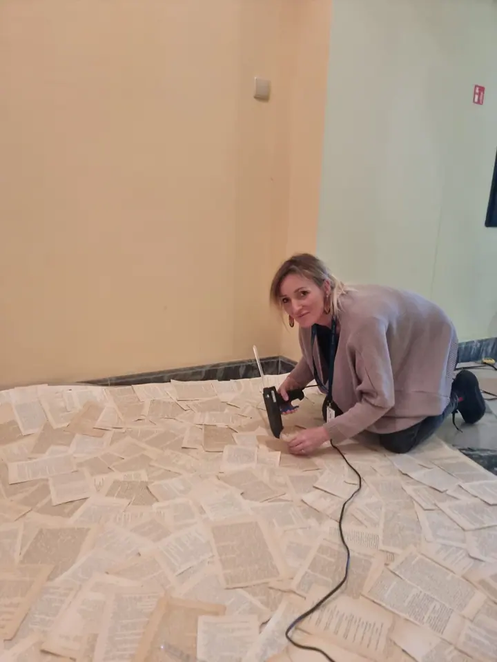 Weronika Walczak przykleja kartki z książek do posadzki przy Schodach Cesarskich