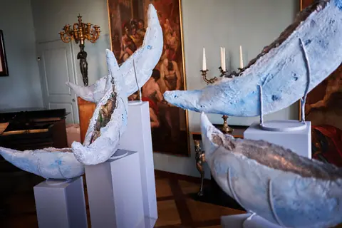 Rzeźby w kształcie łodzi na białych postumentach w zamkowej sali
