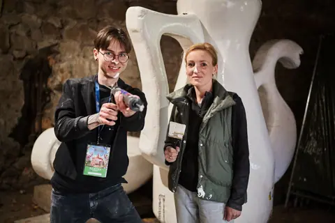 Florystka i wolontariusz z pędzlami przy wielkich porcelanowych dzbanach w piwnicy