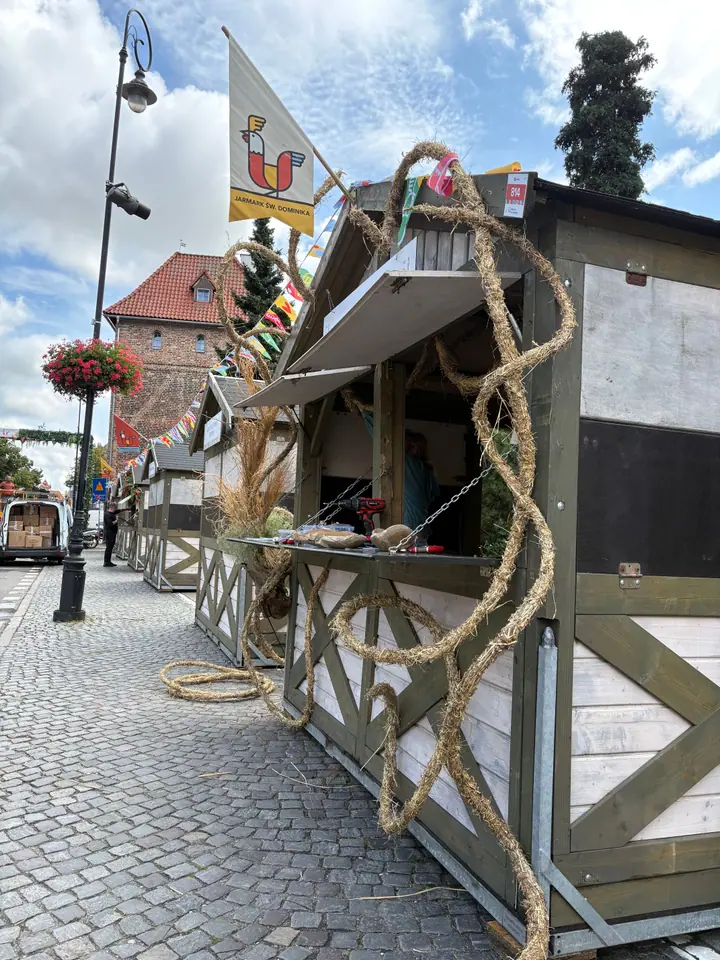 Spirale i pętle ze skręconego siana oplatające narożnik stoiska, w tle flaga jarmarku