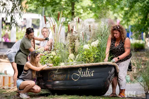 Florystki obsadzają trawami, pałką wodną i hortensjami łódkę z napisem „Romeo i Julia”
